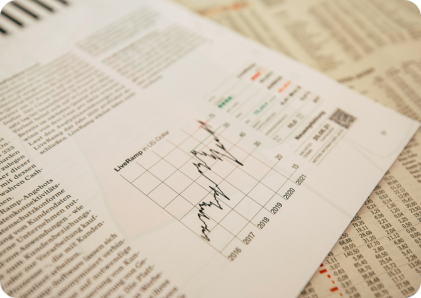Documentos y periódicos financieros con gráficos de tendencias bursátiles impresos sobre una mesa