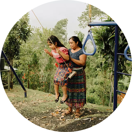 Madre e hija vistiendo trajes tradicionales en un columpio al aire libre