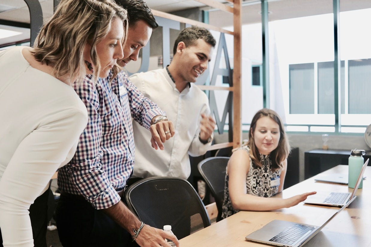 Equipo de trabajo reunido en una oficina, revisando información en computadoras portátiles