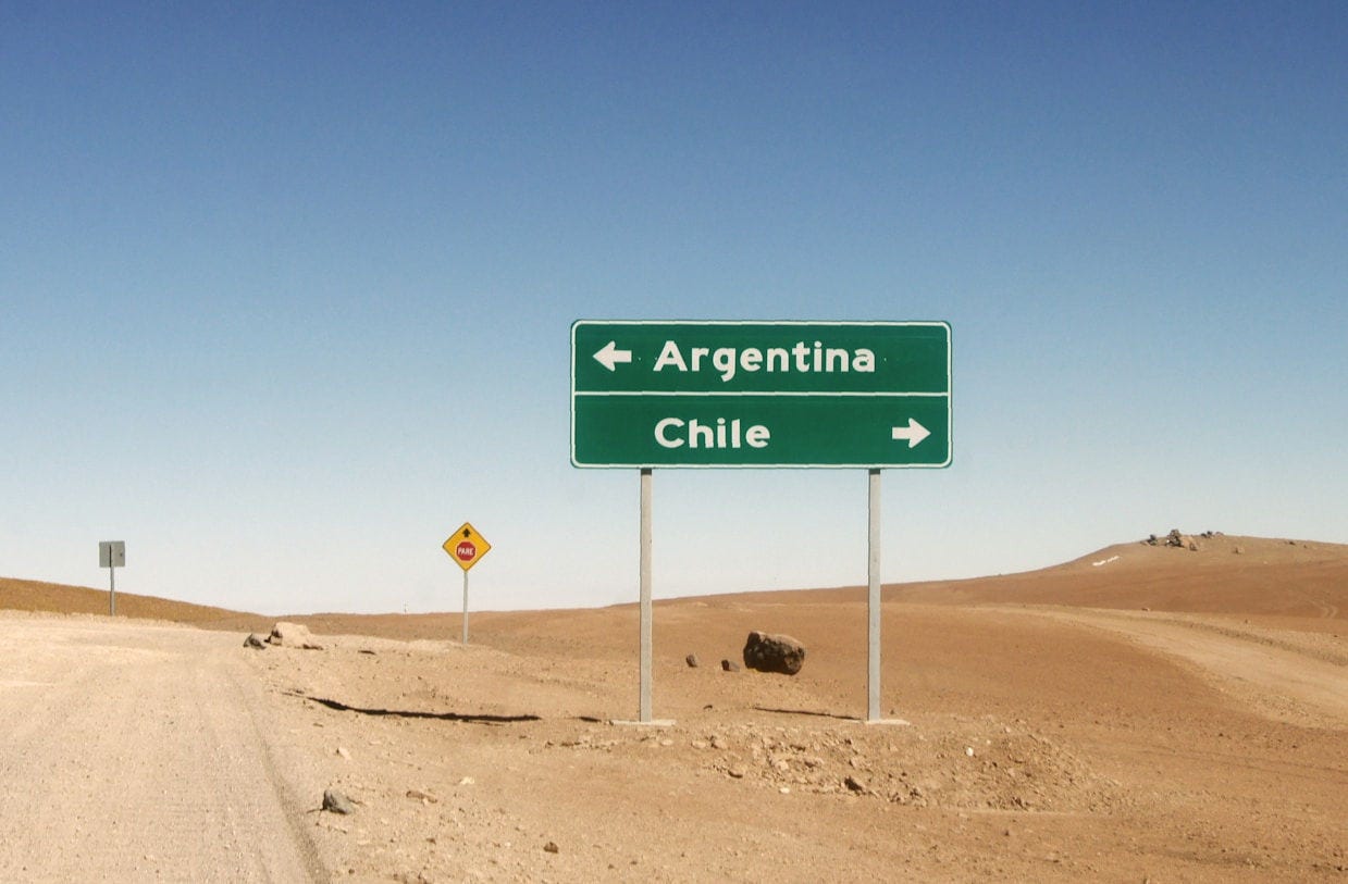 Cartel de carretera señalando Argentina a la izquierda y Chile a la derecha en un paisaje desértico