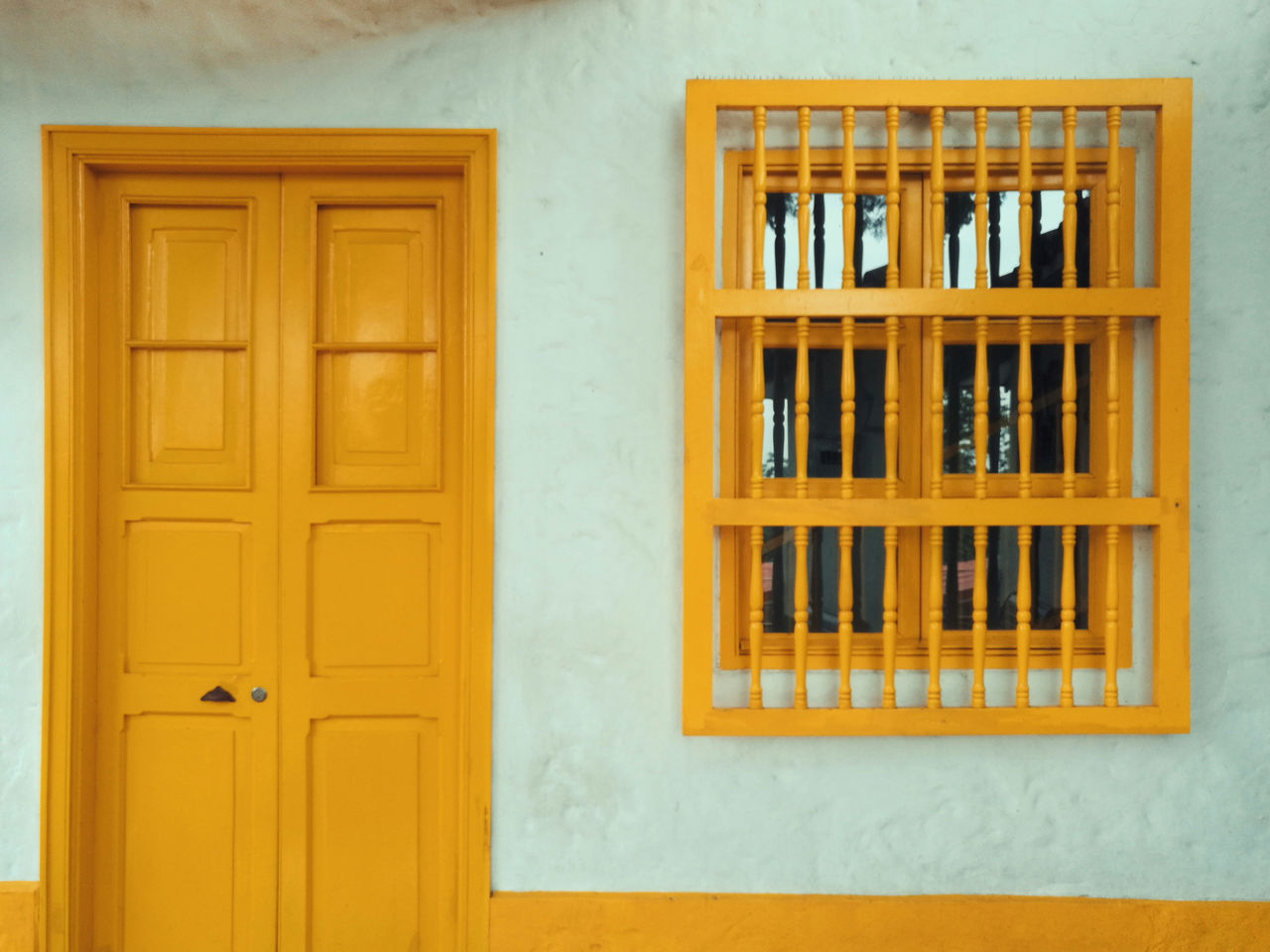 Fachada de edificación tradicional con puerta y ventana de madera amarilla