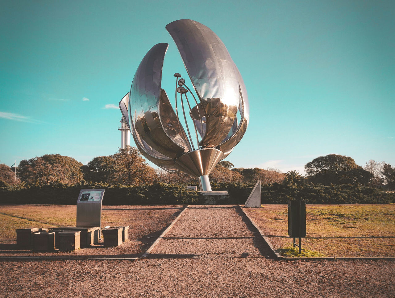 Escultura metálica Floralis Genérica sobre una plaza arbolada con transeúntes