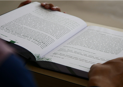 Persona sosteniendo y leyendo un libro abierto sobre una mesa