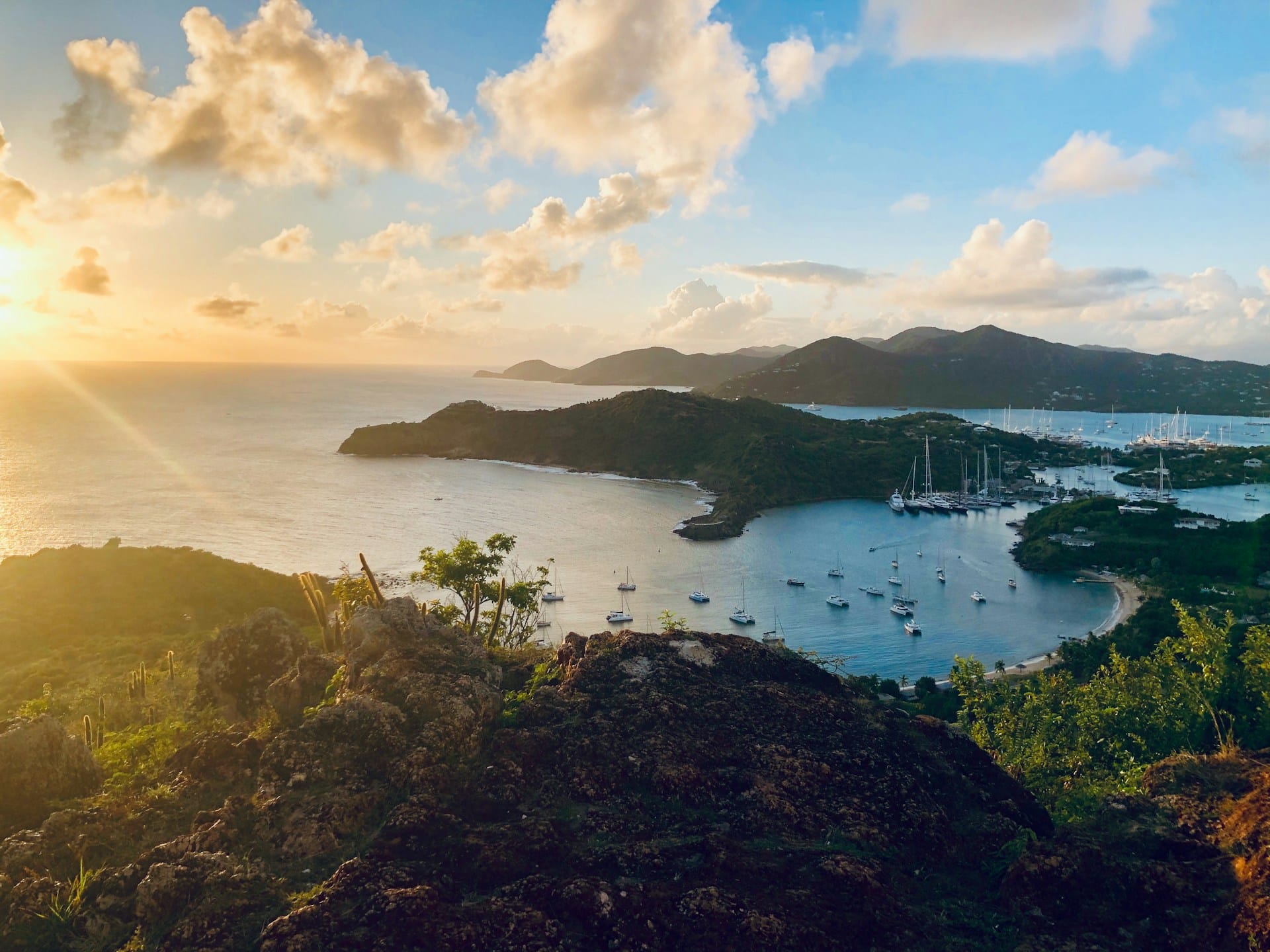 Vista elevada al atardecer de bahías interconectadas y colinas costeras bajo un cielo dorado