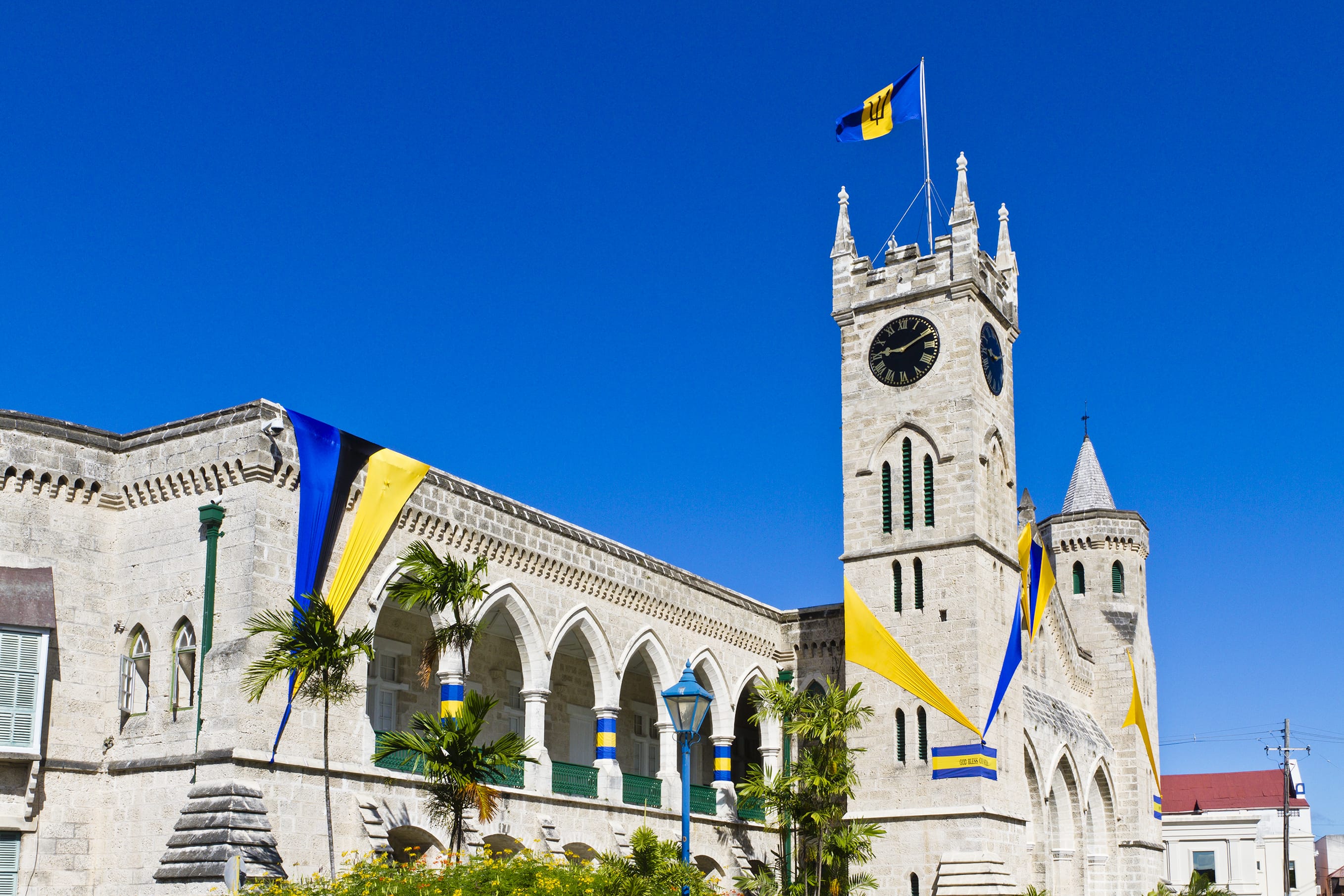 The Parliament Building, completed in 1874, is a masterpiece of Gothic Architecture, built of local coral limestone and strategically placed in the heart of Bridgetown. These buildings house the House of Assembly and the Senate and hold the history of the Barbadian system of Government which is the third oldest political system within the Commonwealth. In this picture, the building facade is adorned with Blue and Gold banners, the colors of Barbados, to celebrate the independence day occurred on 30 November 1966. The celebrations of remembrance continue for the entire month of November.