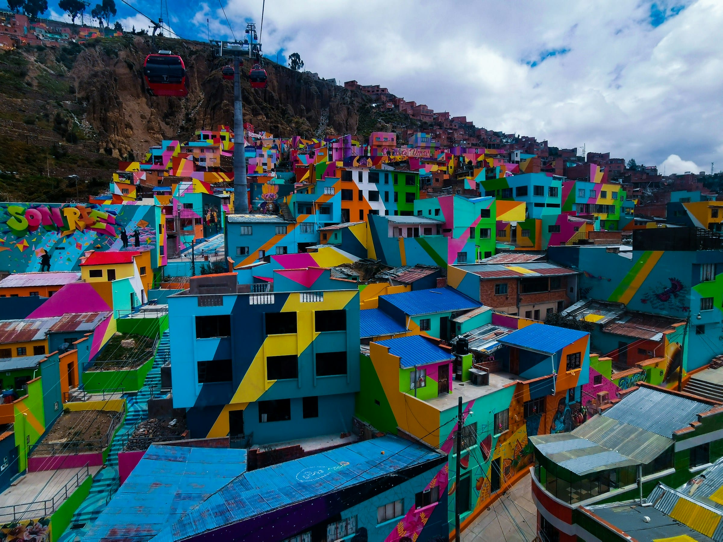 Fachadas de viviendas pintadas con colores vivos y murales artísticos en la ladera de La Paz, Bolivia.