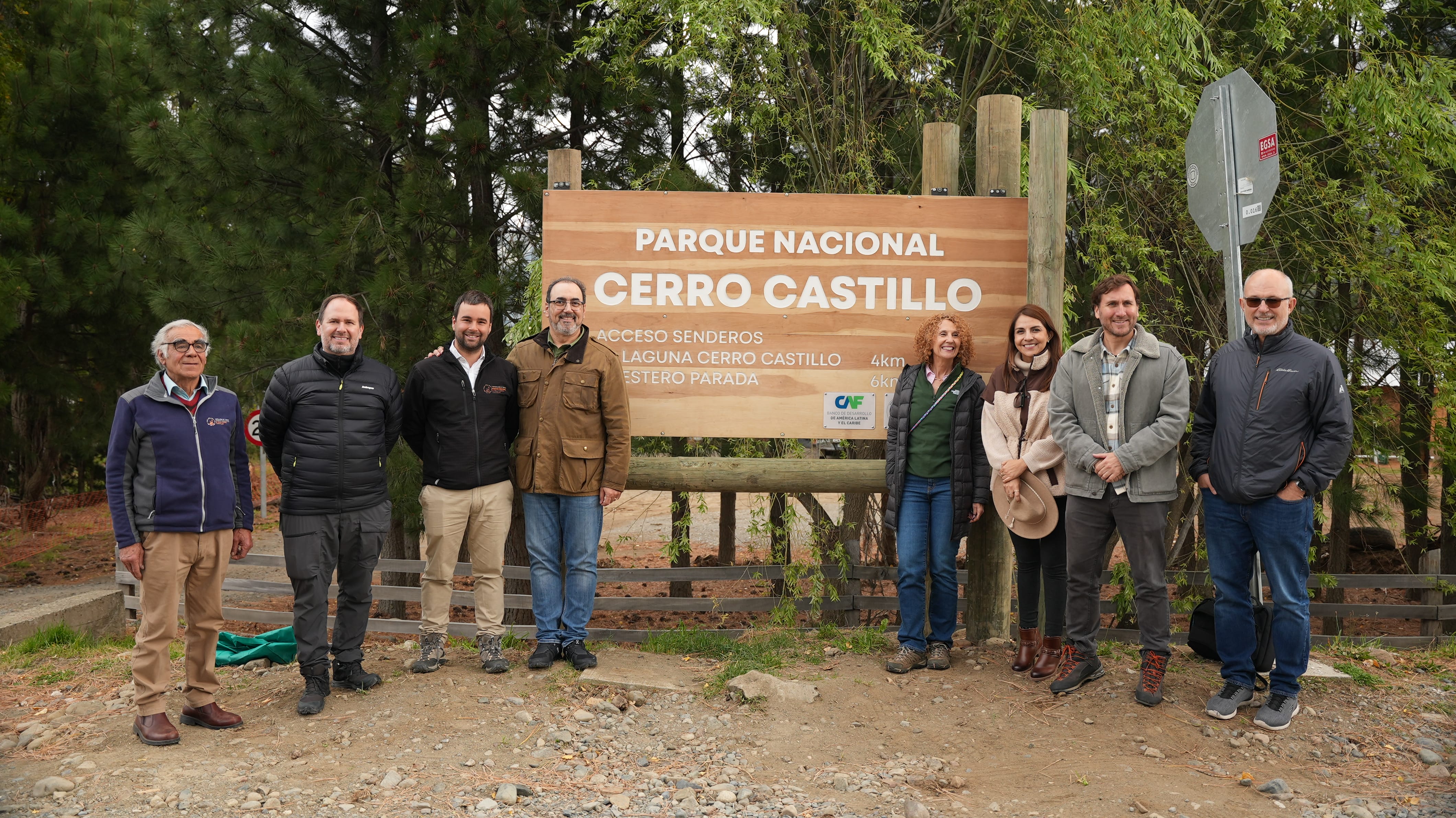 Grupo de personas posando junto al letrero de madera del Parque Nacional Cerro Castillo en la Patagonia chilena.