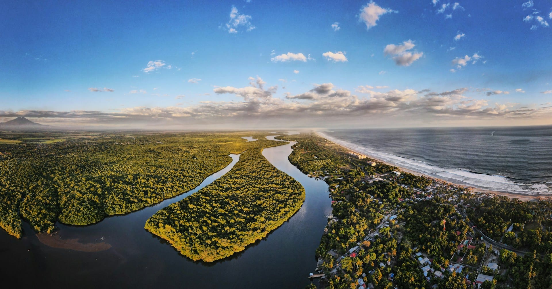 Panorámica aérea de manglares, canal serpenteante de agua y desembocadura en el Océano Pacífico.