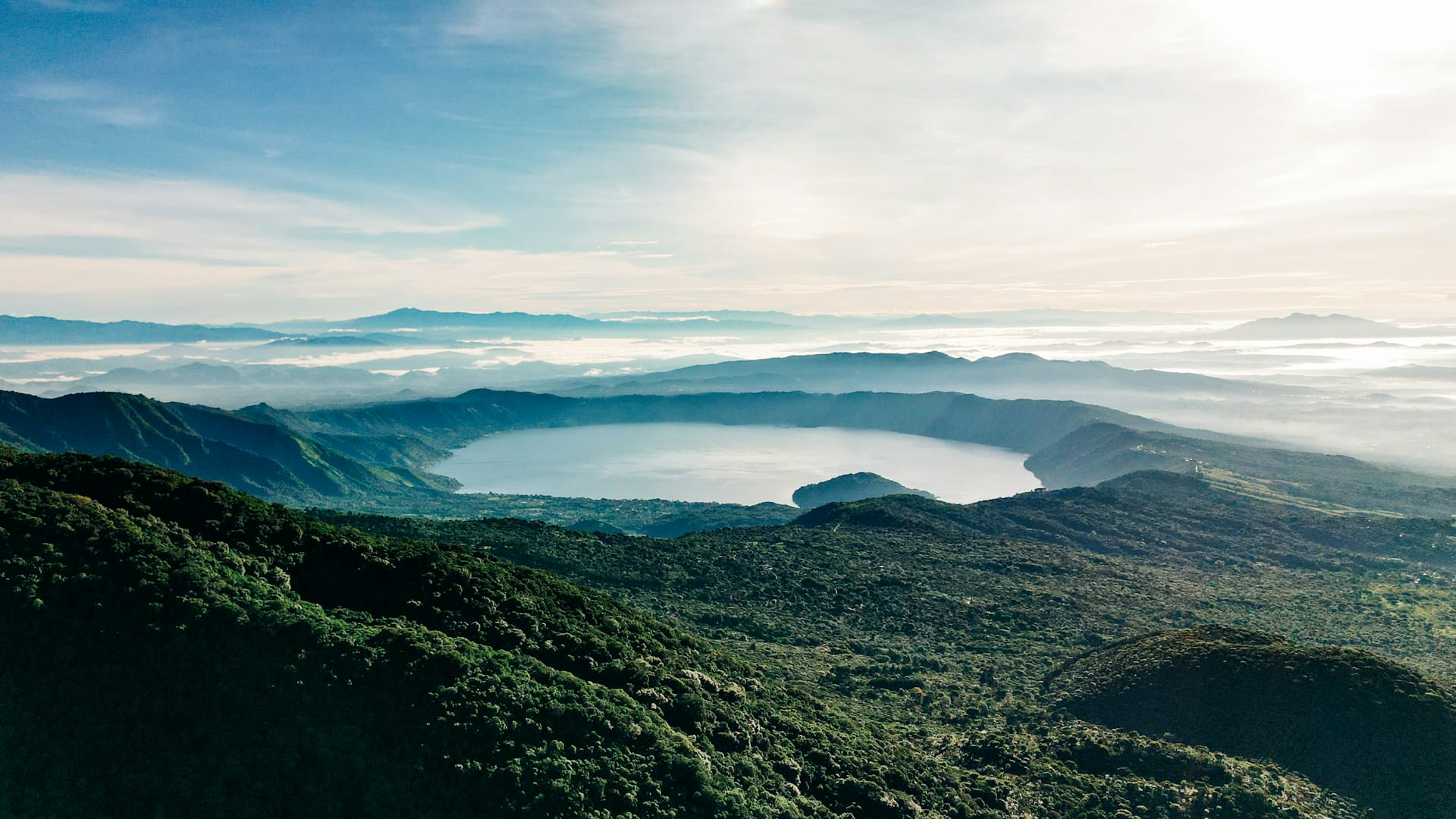 Vista panorámica del lago de origen volcánico Coatepeque rodeado de vegetación montañosa.