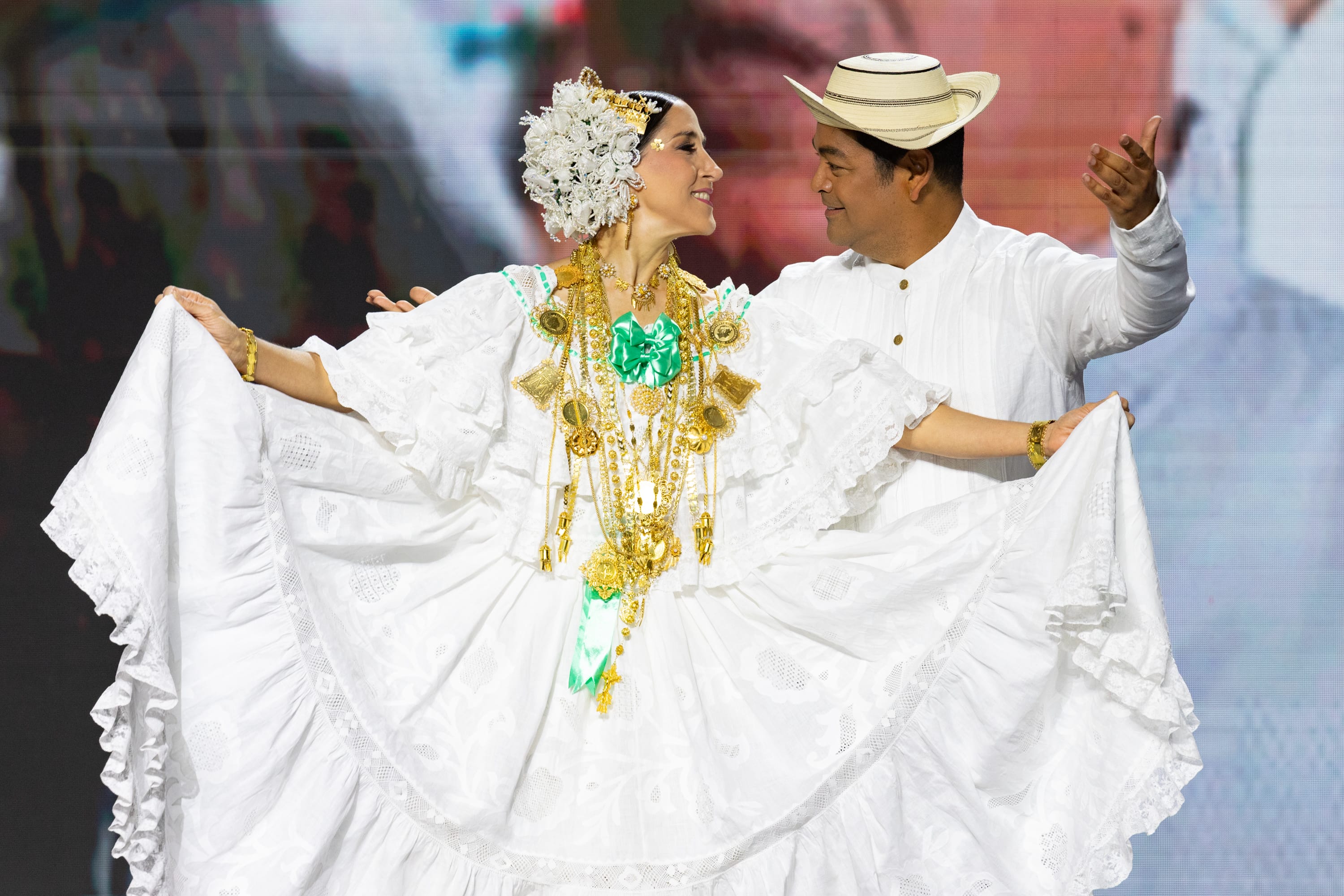 Pareja realizando baile folclórico panameño vestida con el traje tradicional de pollera y montuno.