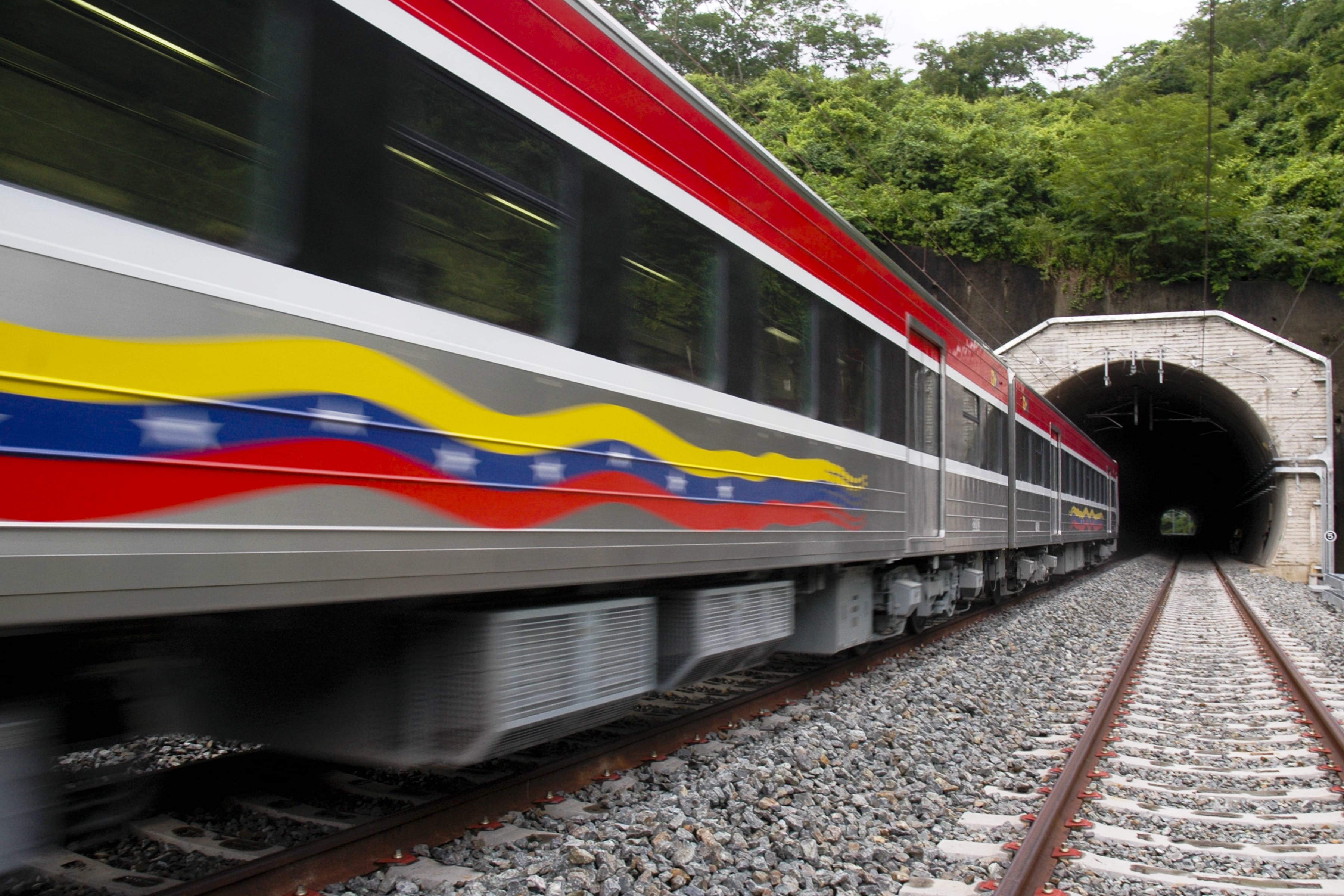 Tren de pasajeros con la bandera de Venezuela saliendo de un túnel en el sistema ferroviario.